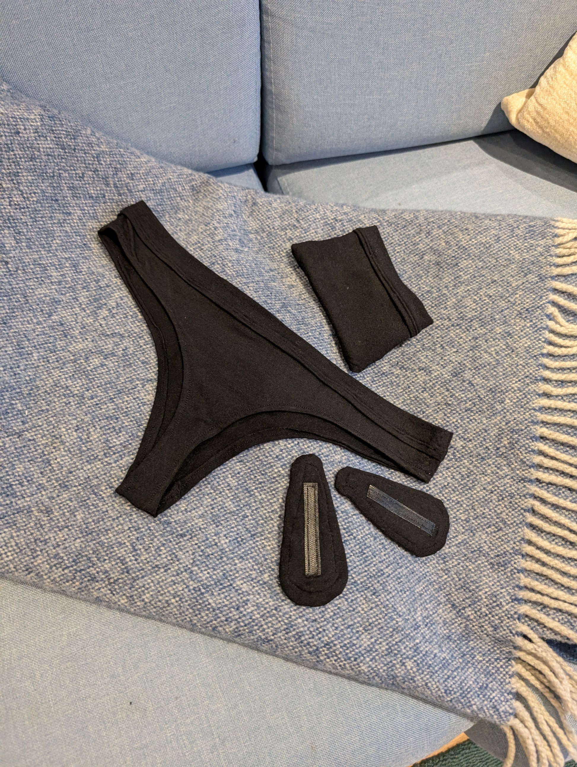 Black thong set on a textured surface with two detachable liners